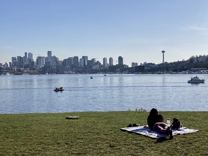caption: A Gas Works Park visitor faces a clear view of the Seattle skyline on March 3, 2021. Like the park, the waterway was packed with locals enjoying the warmer weather.