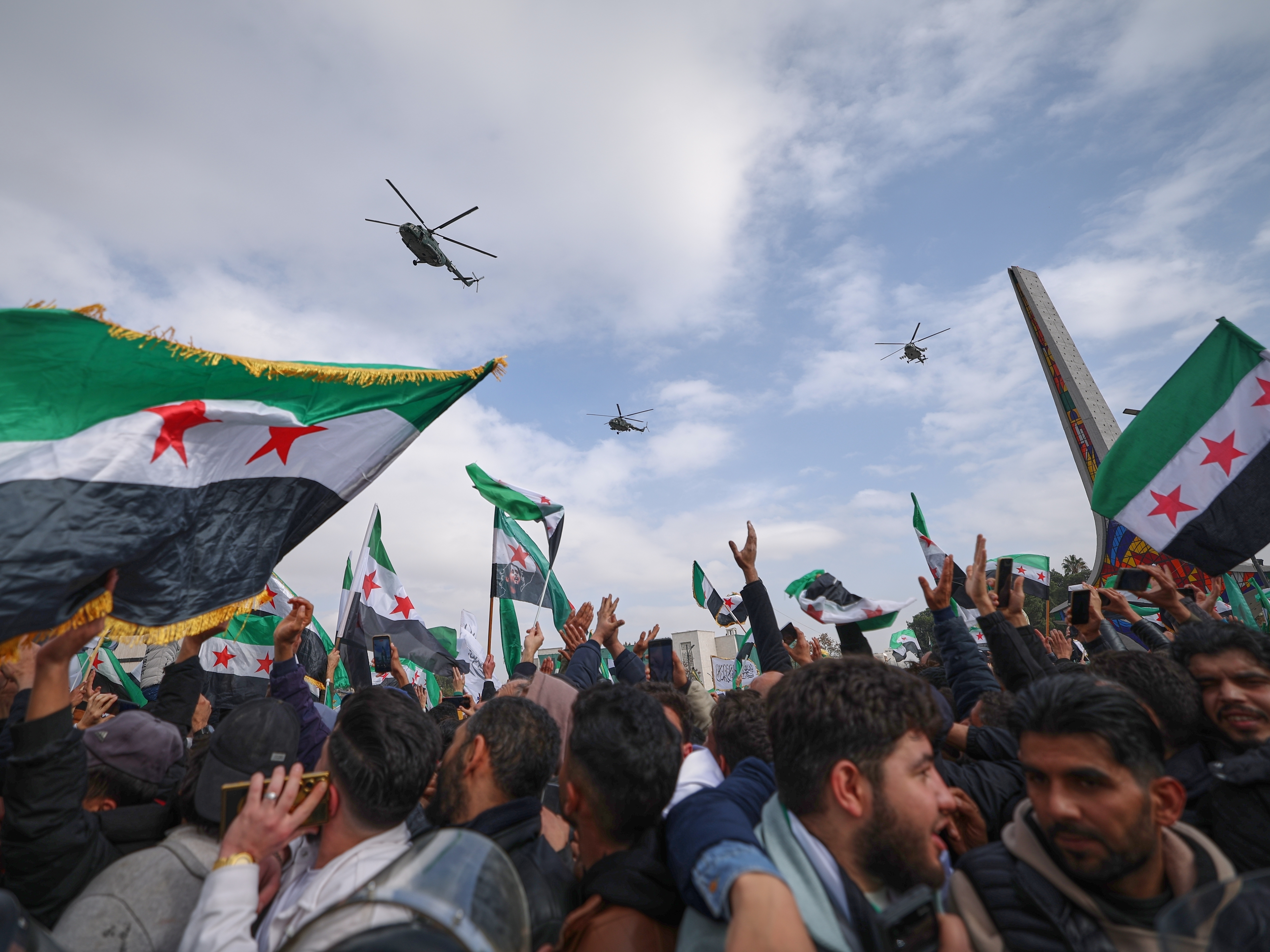 caption: Army helicopters fly overhead during a parade by the new Syrian army marking the first anniversary of the ousting of the Bashar Assad regime in Damascus, Syria, Monday.
