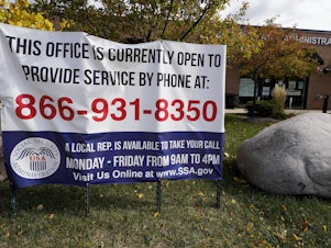 caption: A sign outside a U.S. Social Security Administration office in Mount Prospect, Ill., in October last year. Closed SSA offices across the country are being blamed for a 30 percent drop in applications for an aid program for the most vulnerable.