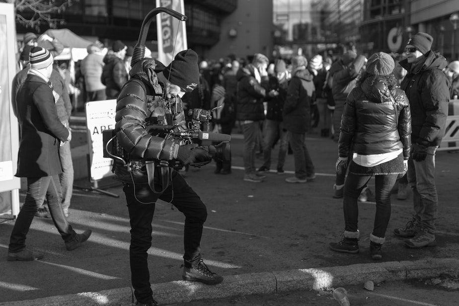 caption: A videographer gathers footage in a crowd.