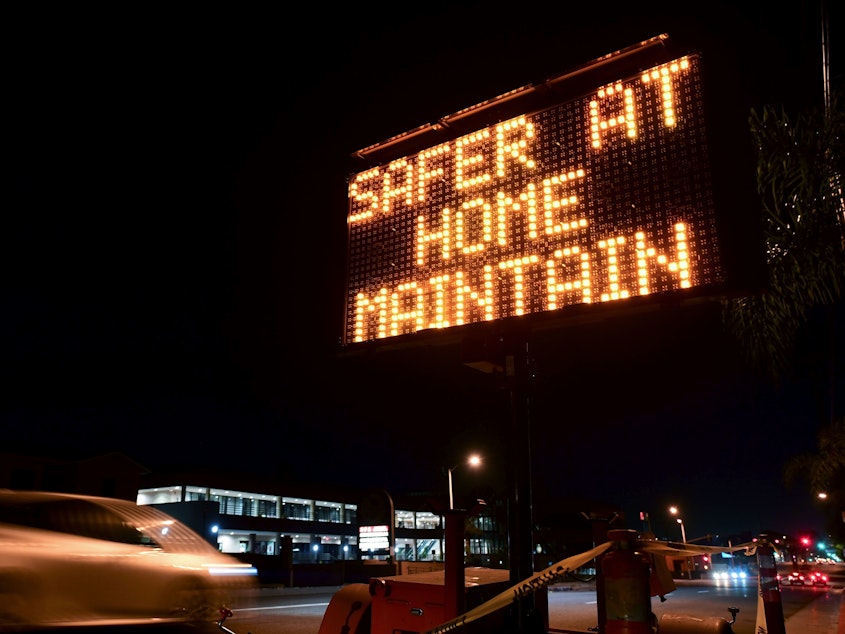 caption: A sign reminds motorists of Los Angeles County's stay-at-home regulation. On Wednesday, the Centers for Disease Control and Prevention rolled out its revised guidelines for people potentially exposed to the coronavirus.