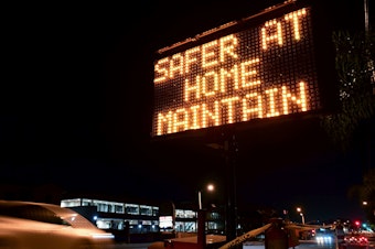 caption: A sign reminds motorists of Los Angeles County's stay-at-home regulation. On Wednesday, the Centers for Disease Control and Prevention rolled out its revised guidelines for people potentially exposed to the coronavirus.