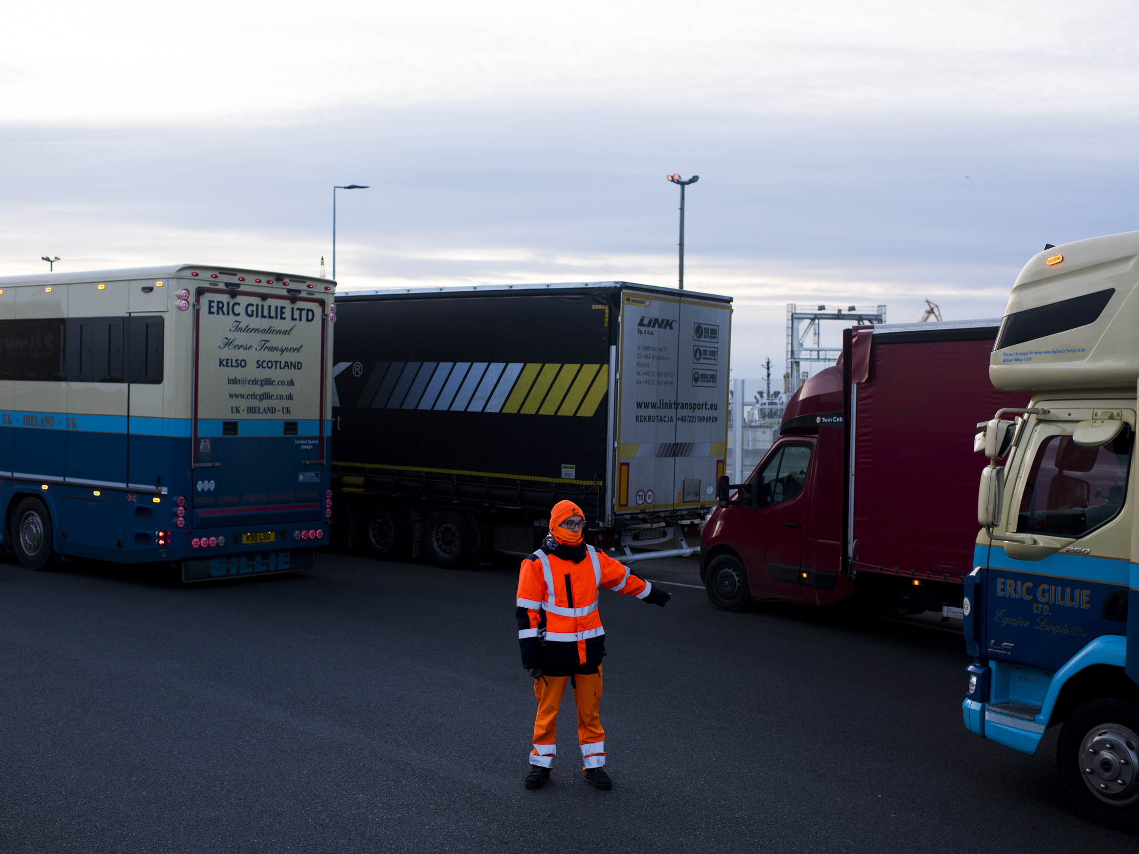 caption: A worker directs trucks where to wait in line in order to board ferries to the United Kingdom in Calais, France. Twenty percent of British imports pass through the port of Calais.