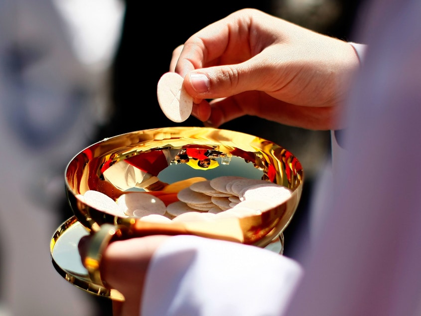 caption: A priest holds a Holy Communion wafer in Washington, D.C.