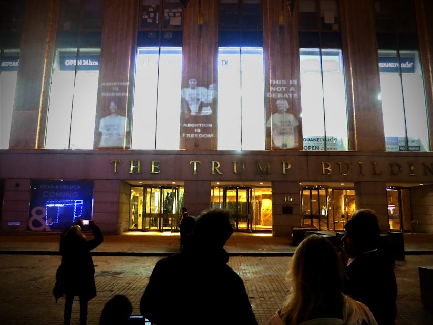caption: Shout Your Abortion projections cover the Trump Building on Wall Street in NYC for the 44th anniversary of Roe v. Wade. These visuals were projected and facilitated by NYC activist crew The Illuminators. 