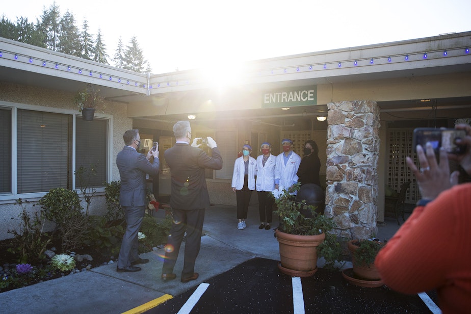 caption: Pharmacists stand near the entrance to the Life Care Center of Kirkland as photographs are taken ahead of the administration of the first Pfizer-BioNTech Covid-19 vaccines on Monday, December 28, 2020, in Kirkland. 
