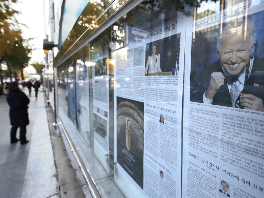 caption: A newspaper's front page featuring President-elect Joe Biden and Vice President-elect Kamala Harris is displayed on a sidewalk in Seoul, South Korea, on Monday.