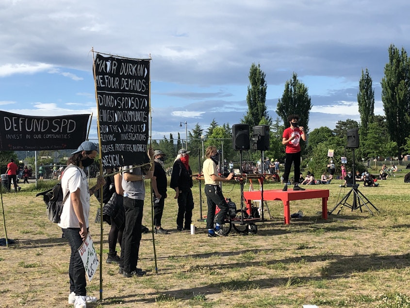 caption: Demonstrators gather for a rally in Magnuson Park ahead of a march to confront Seattle Mayor Jenny Durkan at her residence on June 28, 2020.