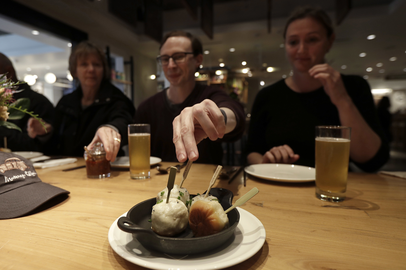 caption: Mike Hardin, center, reaches for a dumpling while dining with others taking a tour with Avital Food Tours at China Live in San Francisco. (Jeff Chiu/AP)