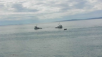caption: The Intruder and the Marathon, two purse-seine boats, rescue the crew of the Aleutian Isle amid flotsam on July 13 off San Juan Island.