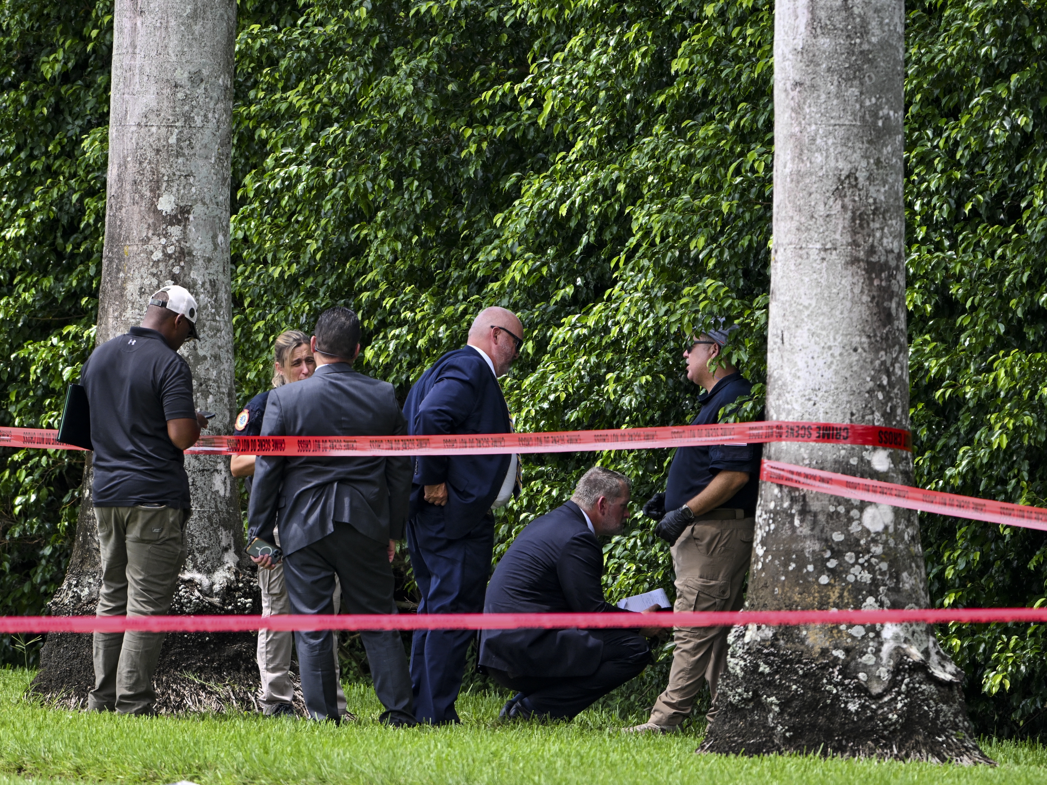 caption: Law enforcement officials work at the crime scene outside the Trump International Golf Club in West Palm Beach, Fla., on September 16, 2024, following the attempted assassination on then-Republican presidential candidate Donald Trump. Ryan Routh is charged in the case and has a federal court hearing on Tuesday in Fort Pierce, Fla.