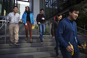 caption: From left, Amazon software development interns Min Vu, Cindy Wang, Jason Mar, Katie Shin and Louis Yang, walk after getting bananas from the Amazon Community Banana Stand outside of the Amazon Meeting Center on Thursday, October 5, 2017, in Seattle. 