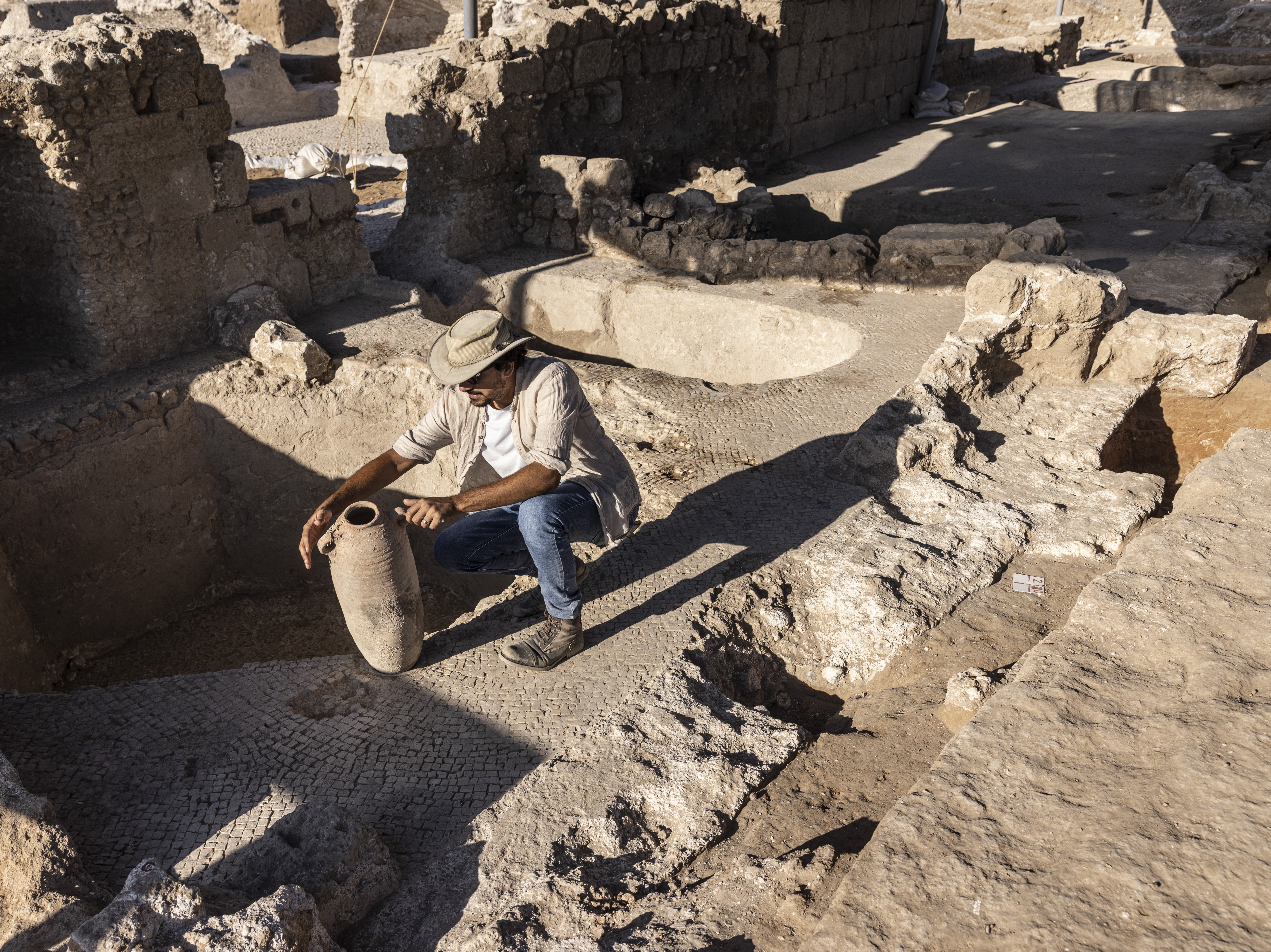 caption: Avshalom Davidesko, from the Israel's Antiquities Authority, examines a jar in a massive ancient winemaking complex dating back some 1,500 years in Yavne, south of Tel Aviv, Israel.