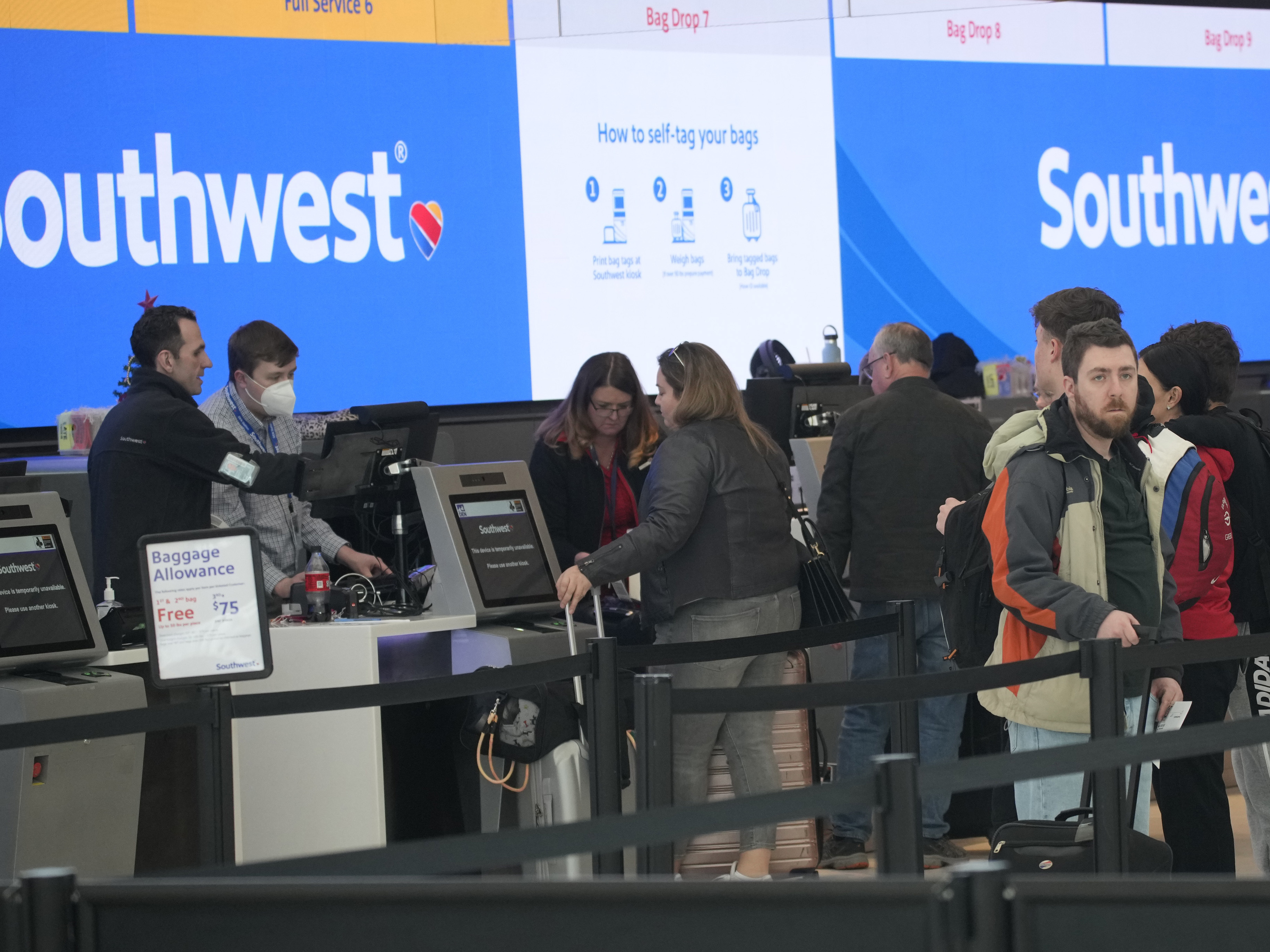 caption: Travelers are shown lining up at the check-in counters for Southwest Airlines in Denver International Airport, Friday, Dec. 30, 2022, in Denver.