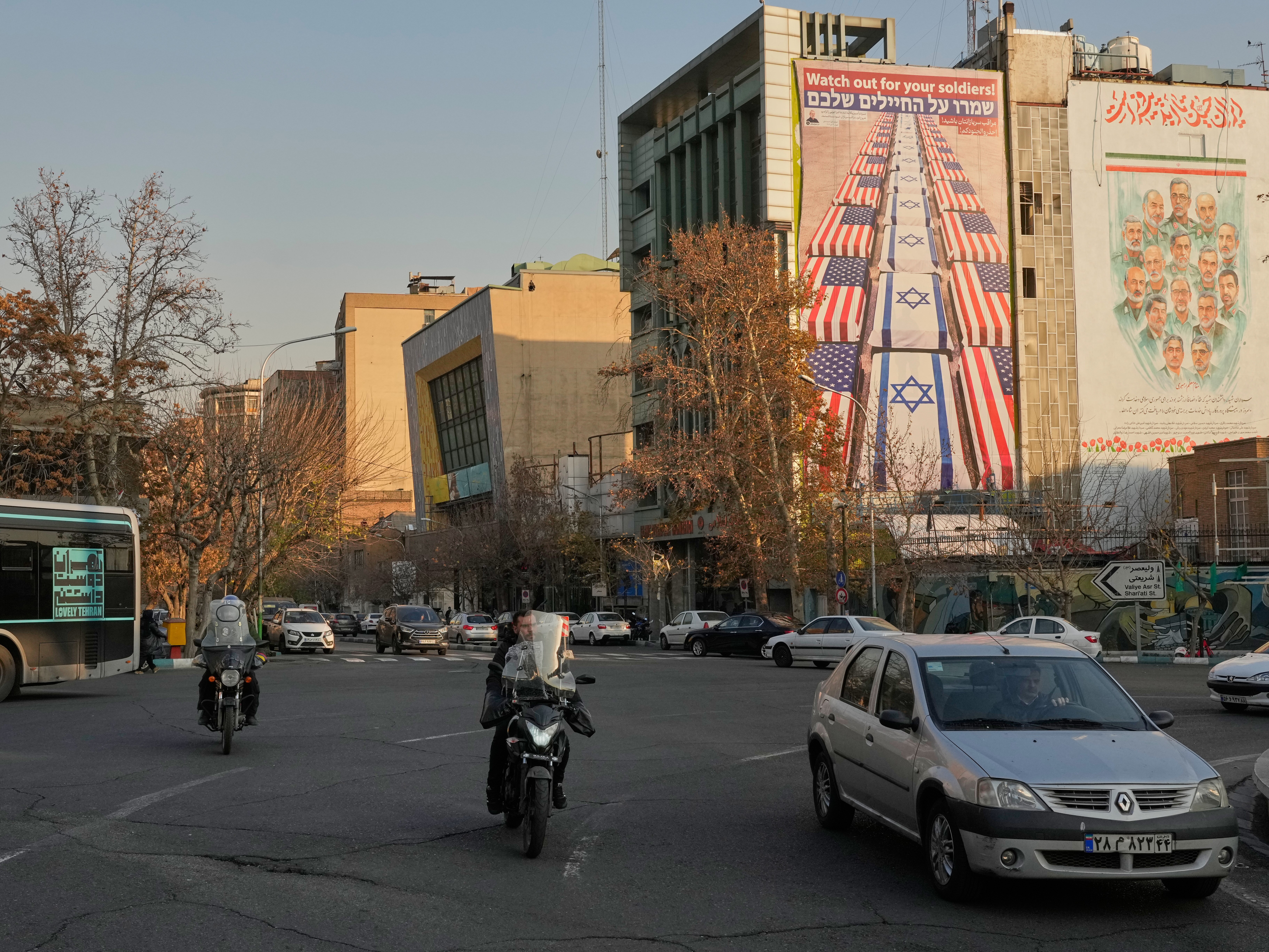 caption: Vehicles in Tehran drive past banners at the Felestin (Palestine) Square with anti-U.S. and anti-Israel messages and portraits of Iranian armed forces commanders and nuclear scientists who were killed  last June in Israeli strikes, Jan. 4.