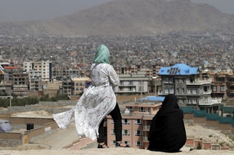 caption: Afghan women look at the skyline of Kabul in September.
