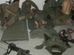 caption: Alon Keren (left) and soldiers from his commando unit sleep on the floor of an evacuated Palestinian home in Gaza.