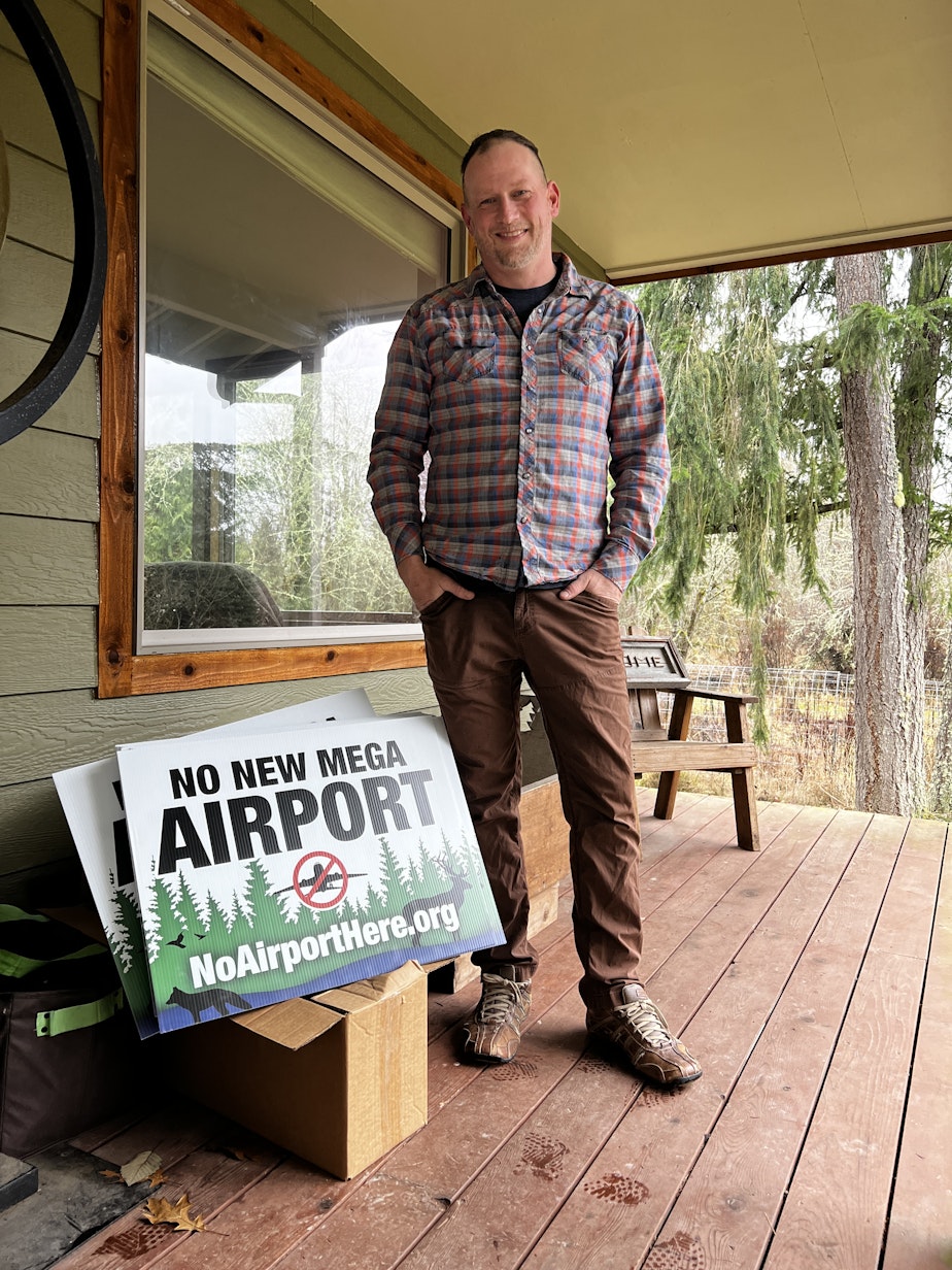 caption: Jake Pool, pictured on his porch. Pool and a number of others are paying out of pocket to create and distribute "No New Mega Airport" signs throughout south Pierce County. 