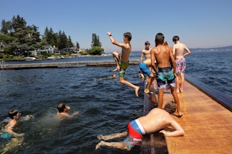 caption: Children jump off the dock at the Laurelhurst Beach Club, a private residential club in Northeast Seattle on Monday, June 28, 2021. 