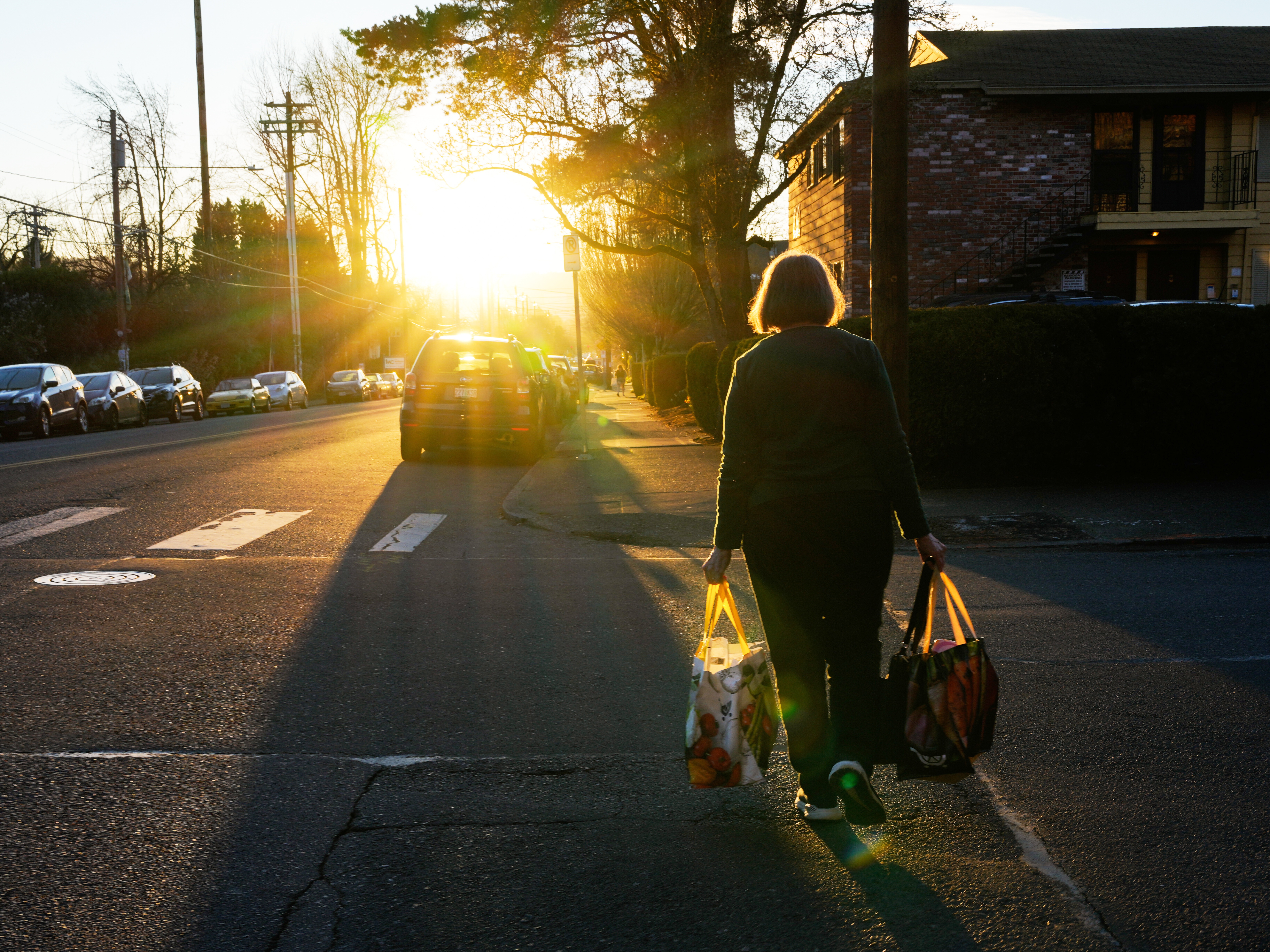 caption: A woman carries reusable shopping bags to her car on Monday, March 16, 2026, in Portland, Ore.