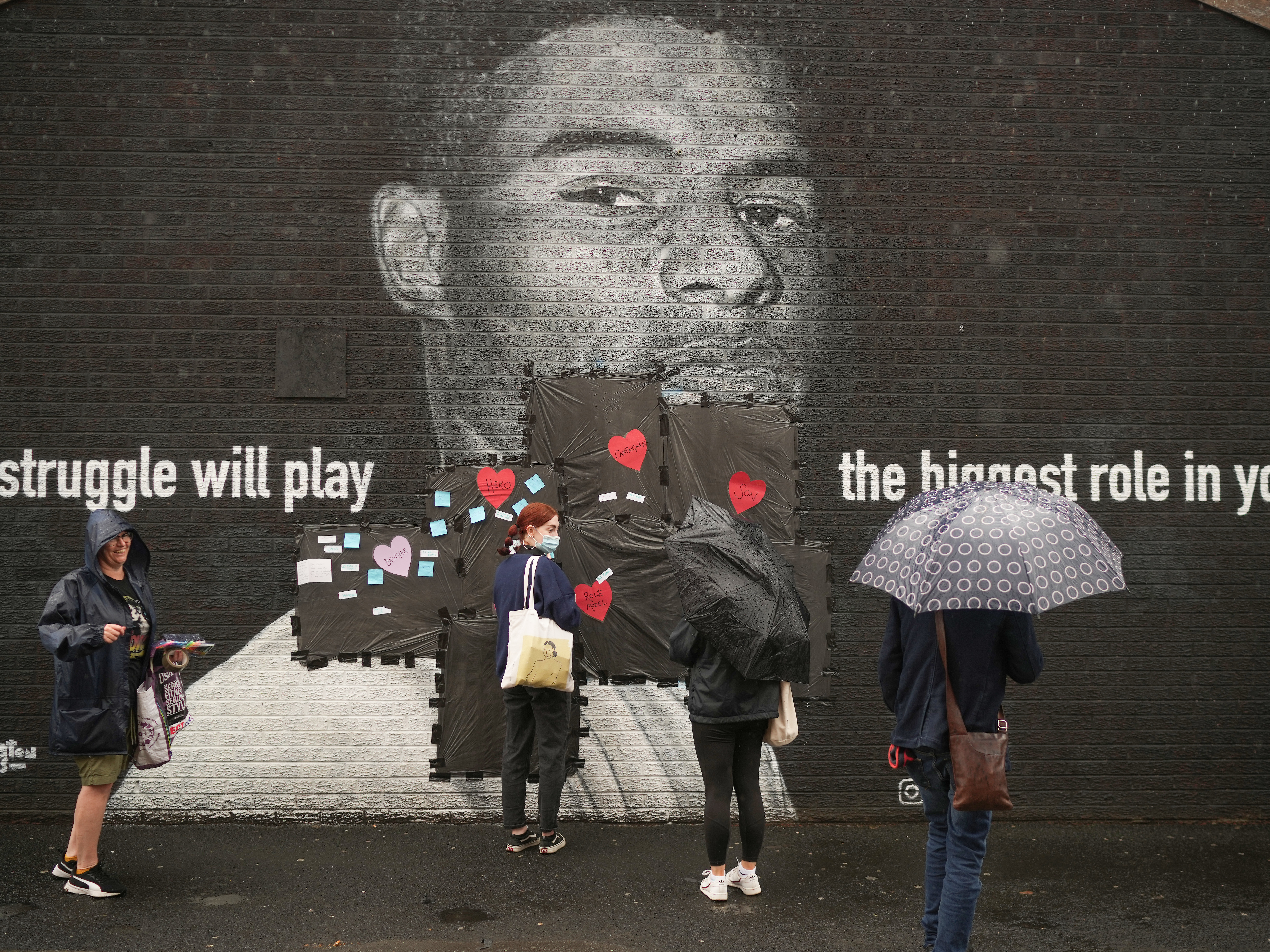 caption: People place supportive messages over the defaced mural of Marcus Rashford, the 23-year-old English soccer star who has faced racist harassment after missing a penalty kick in England's loss to Italy in the Euro finals.
