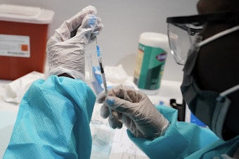 caption: A health care worker fills a syringe with the Pfizer COVID-19 vaccine at the American Museum of Natural History in New York earlier this year.