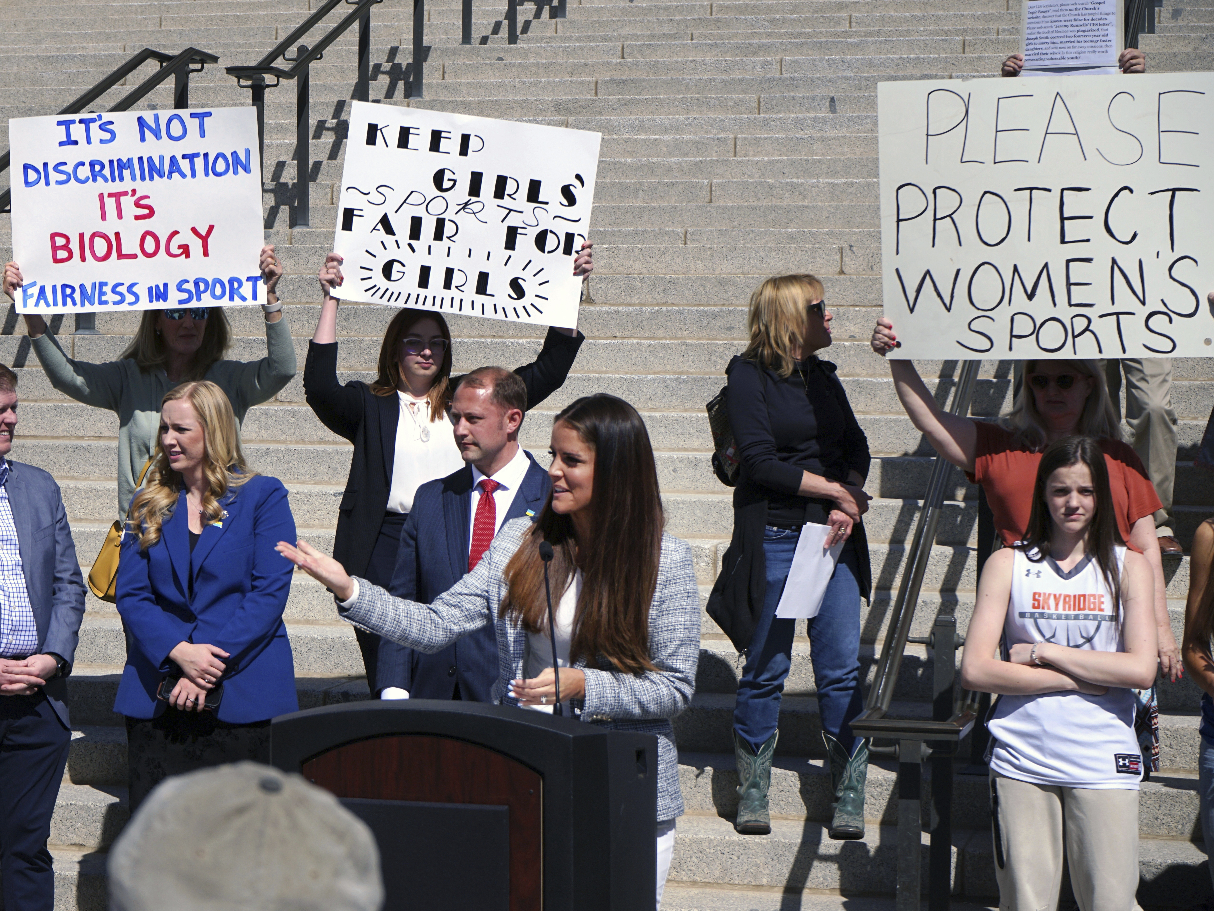caption: State Rep. Kera Birkeland, a Republican high school basketball coach who led Utah's efforts to ban transgender girls from youth sports, addresses a crowd of supporters on the steps of the Utah State Capitol on Friday in Salt Lake City.