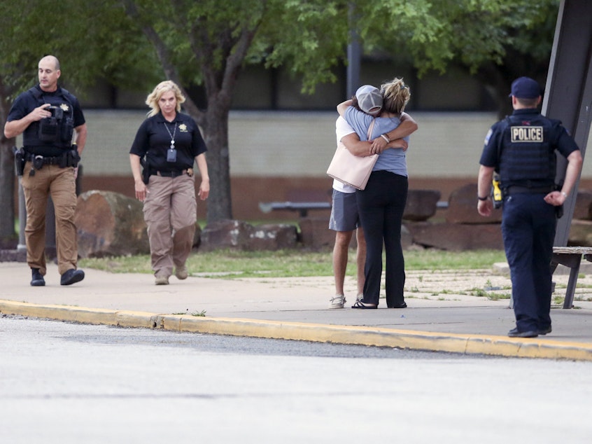 caption: Two people hug outside at Memorial High School where people were evacuated from the scene of a shooting at the Natalie Medical Building on Wednesday, in Tulsa, Okla.