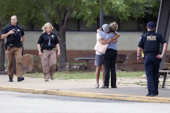 caption: Two people hug outside at Memorial High School where people were evacuated from the scene of a shooting at the Natalie Medical Building on Wednesday, in Tulsa, Okla.