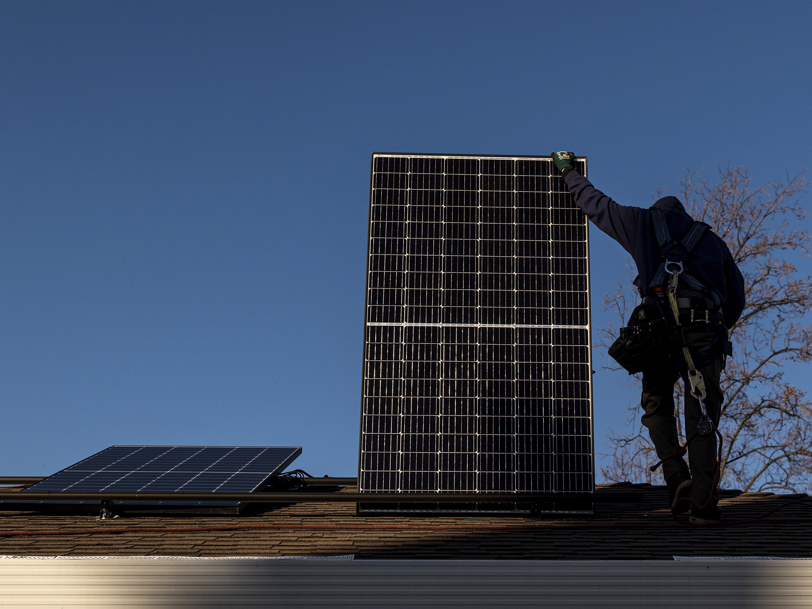caption: A contractor installs a solar panel on the roof of a home. Uncertainty over the future of a 30% federal tax credit has some homeowners rushing to get panels hooked to the grid before Trump becomes President.