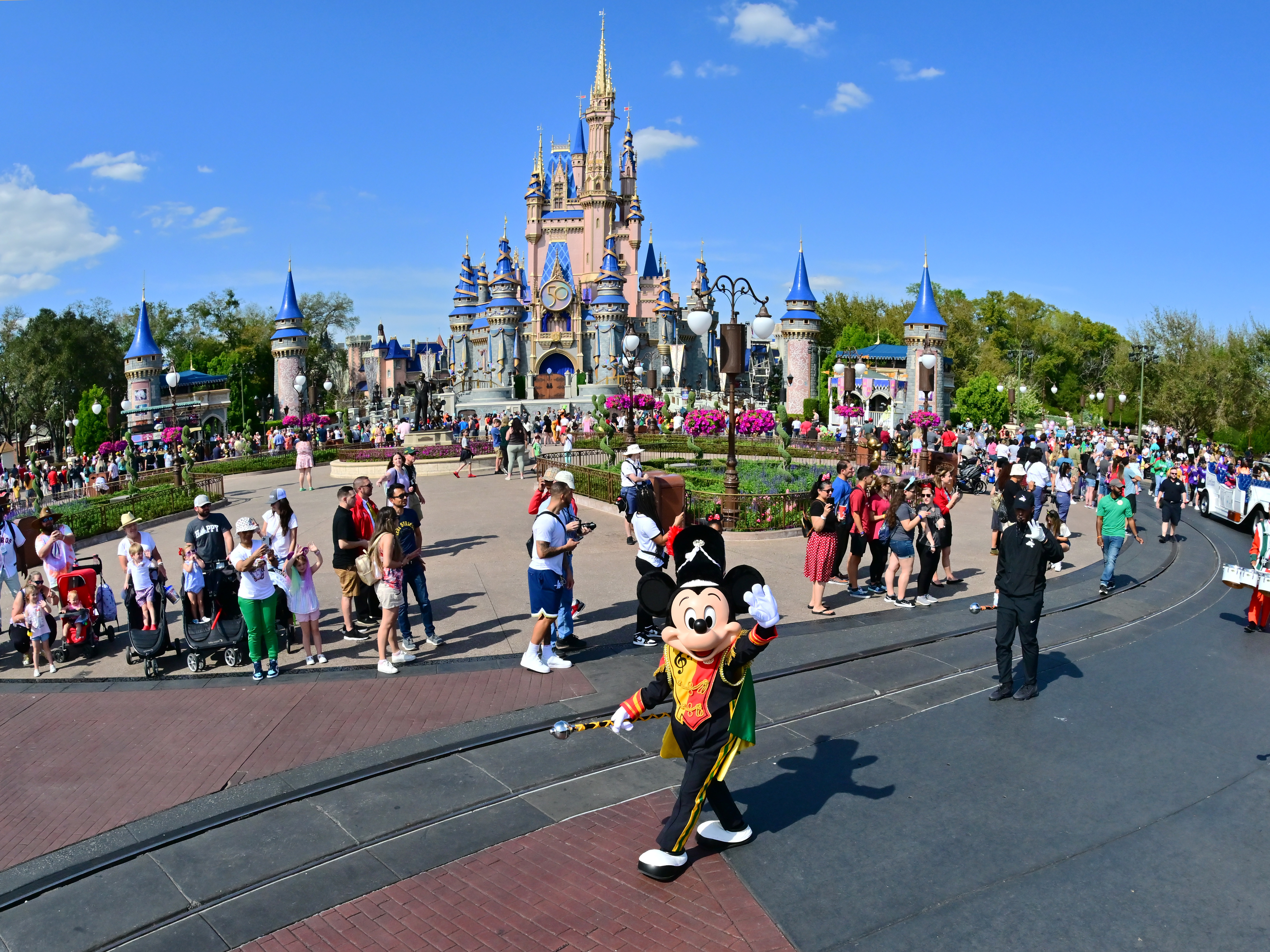 caption: Mickey Mouse waves to fans during a parade at Walt Disney World Resort on March 03, 2022 in Lake Buena Vista, Florida.