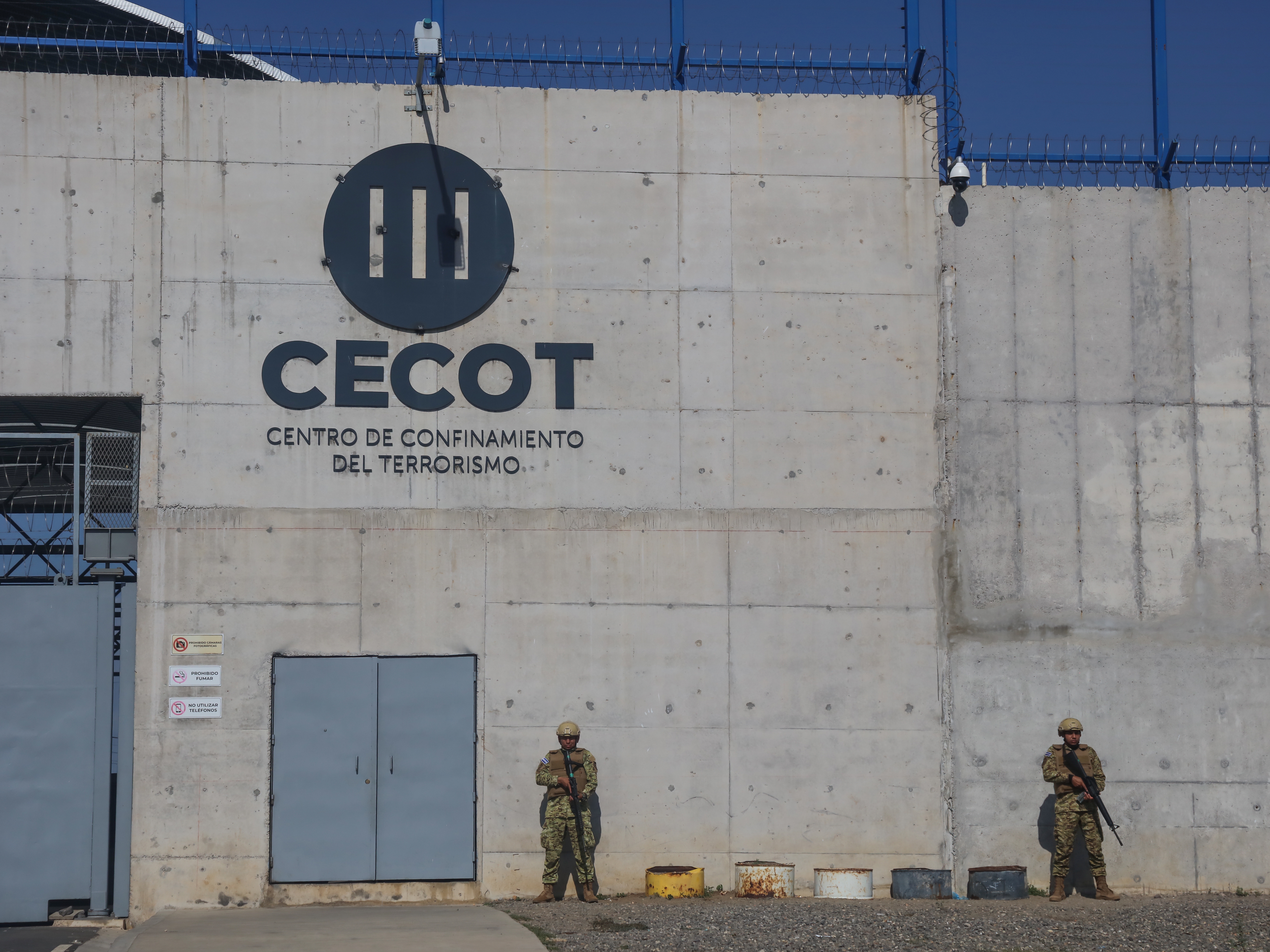 caption: Members of the Salvadorian army stand guard at maximum security penitentiary CECOT on April 4, in Tecoluca, San Vicente, El Salvador.
