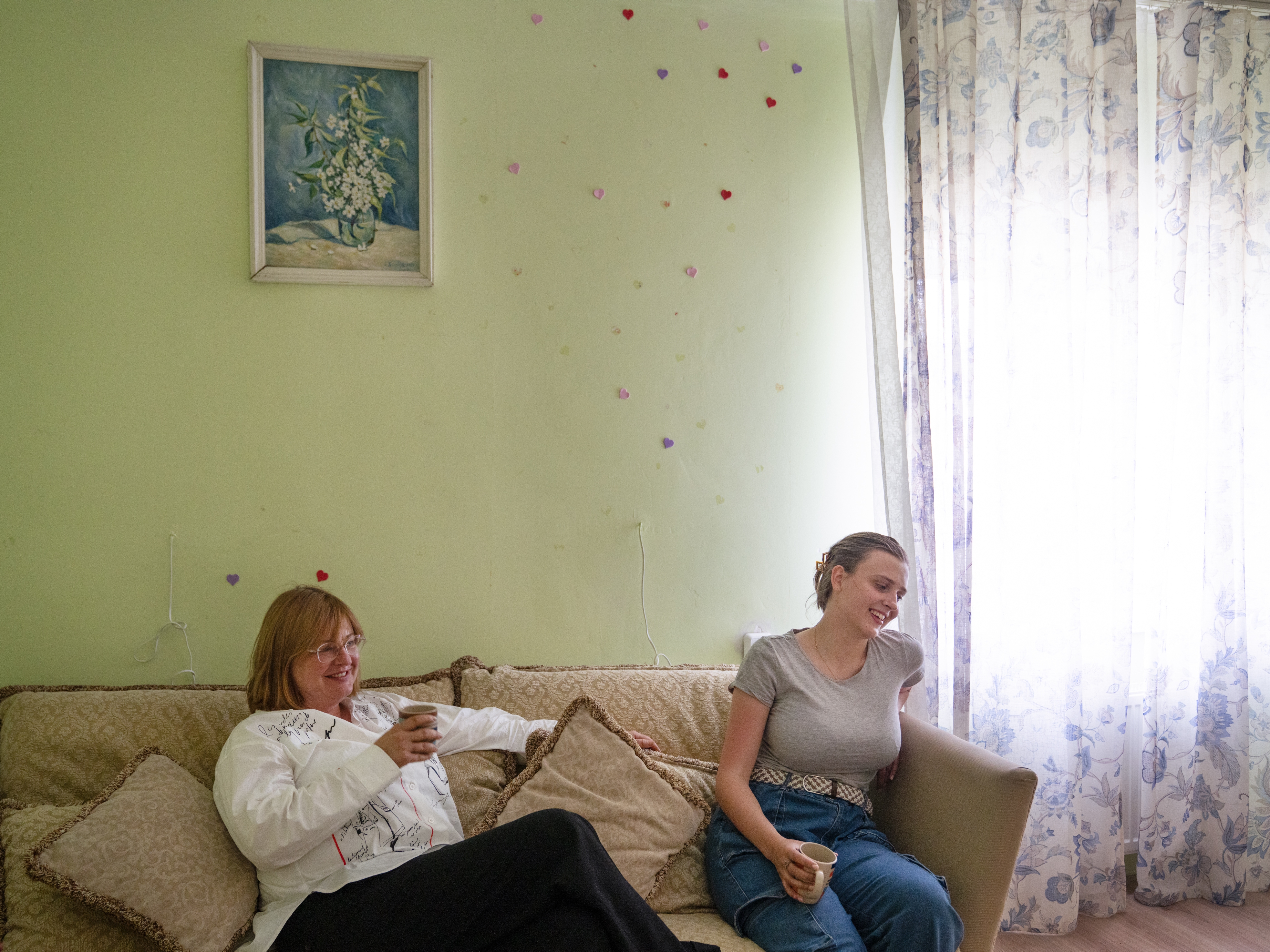 caption: Iryna Schestova, 50, and her daughter, Liia Kazakova, 26, sit in the living room of a friend's home in Horenychi, a suburb of Kyiv, Ukraine. Kazakova is staying in the home instead of with her mother because she can't sleep at night listening to the sounds of war from her mother's apartment in central Kyiv.