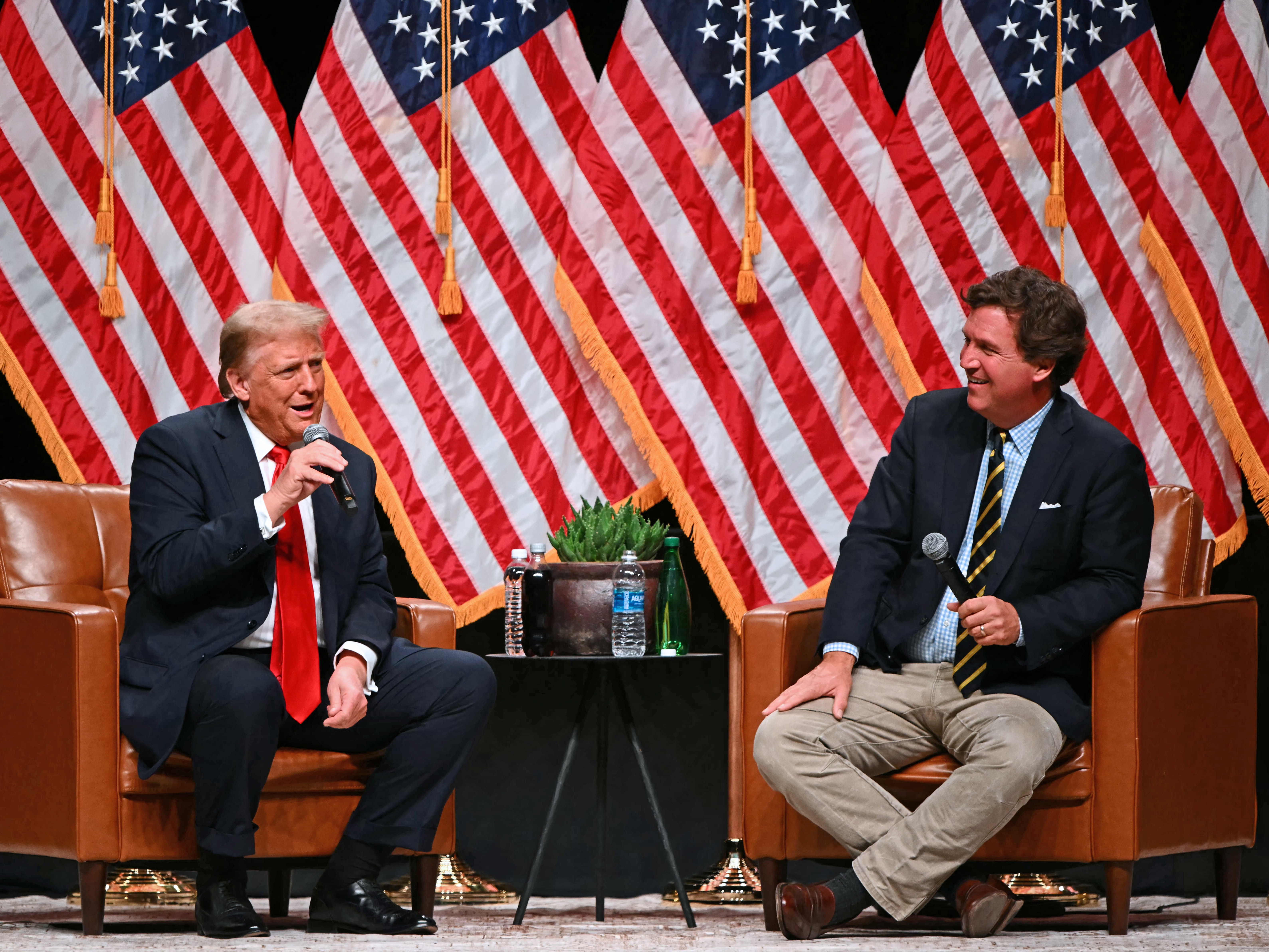 caption: Former President Donald Trump speaks with conservative commentator Tucker Carlson in Glendale, Ariz., on Oct. 31, 2024.