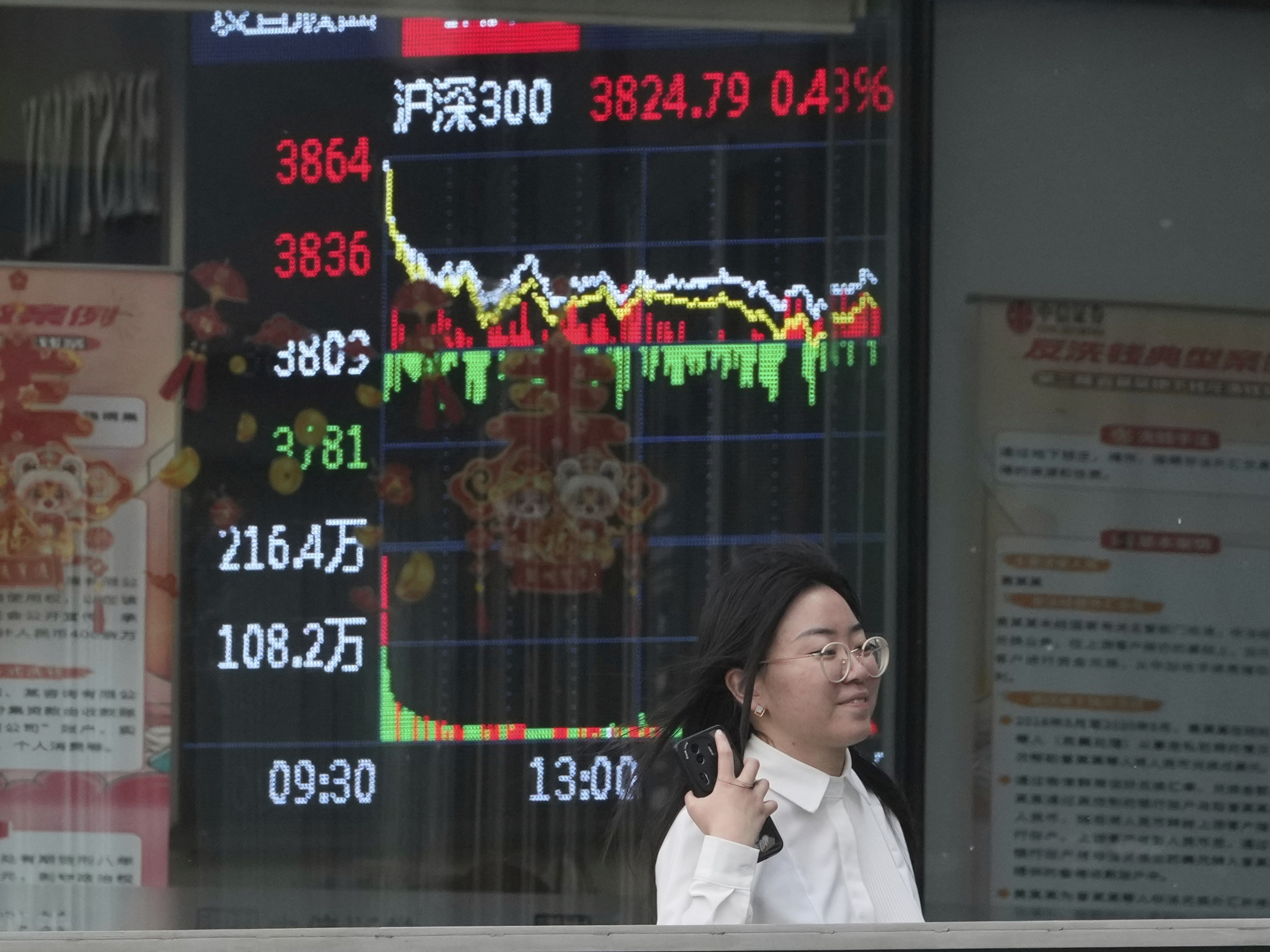 caption: A woman passes by a stock index at a brokerage in Beijing, Wednesday.