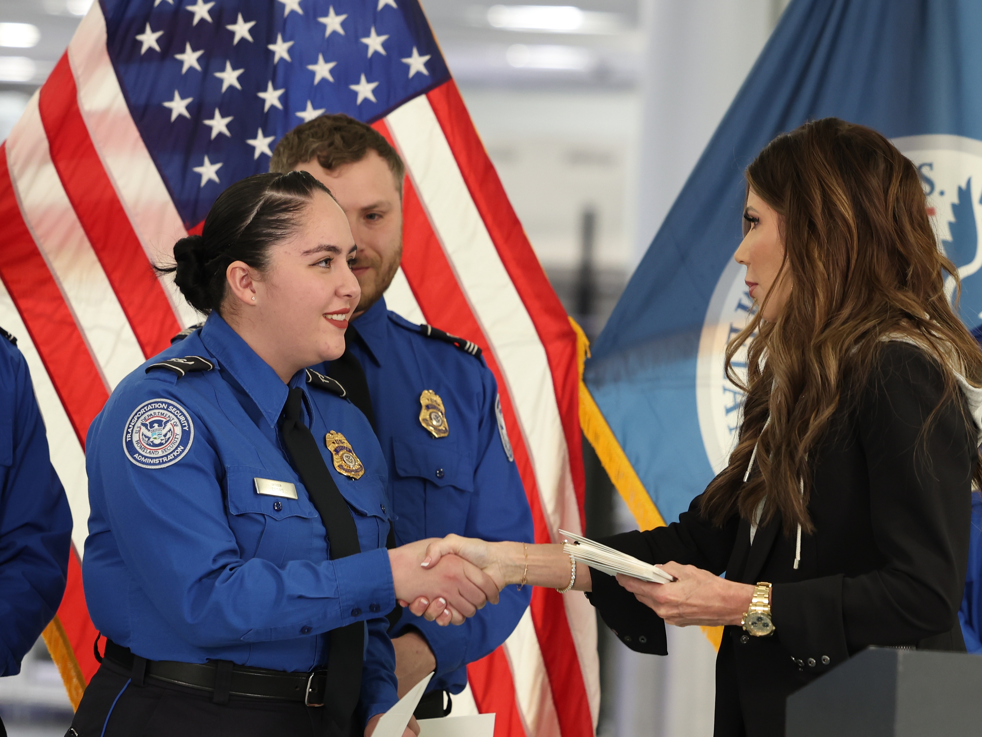 caption: FILE - U.S. Homeland Security Secretary Kristi Noem, right, shakes hands with Transportation Security Administration Officer Monica Degro at a news conference at Harry Reid International Airport, Nov. 22, 2025, in Las Vegas.