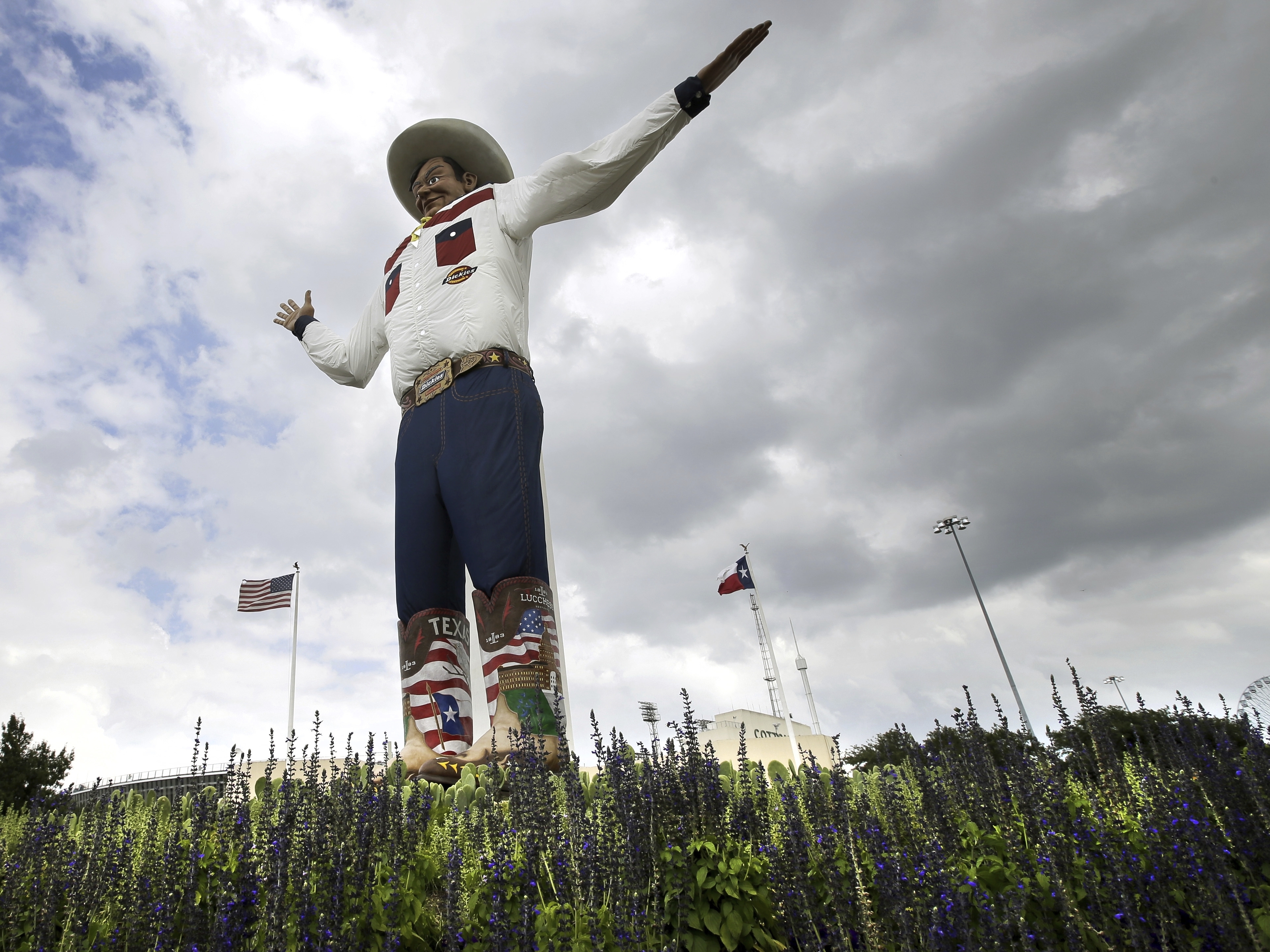caption: Bluebonnets, the state flower of Texas, is shown surrounding Big Tex as storm clouds move in above, Friday, Sept. 27, 2013, in Dallas.  (AP Photo/Tony Gutierrez, File)