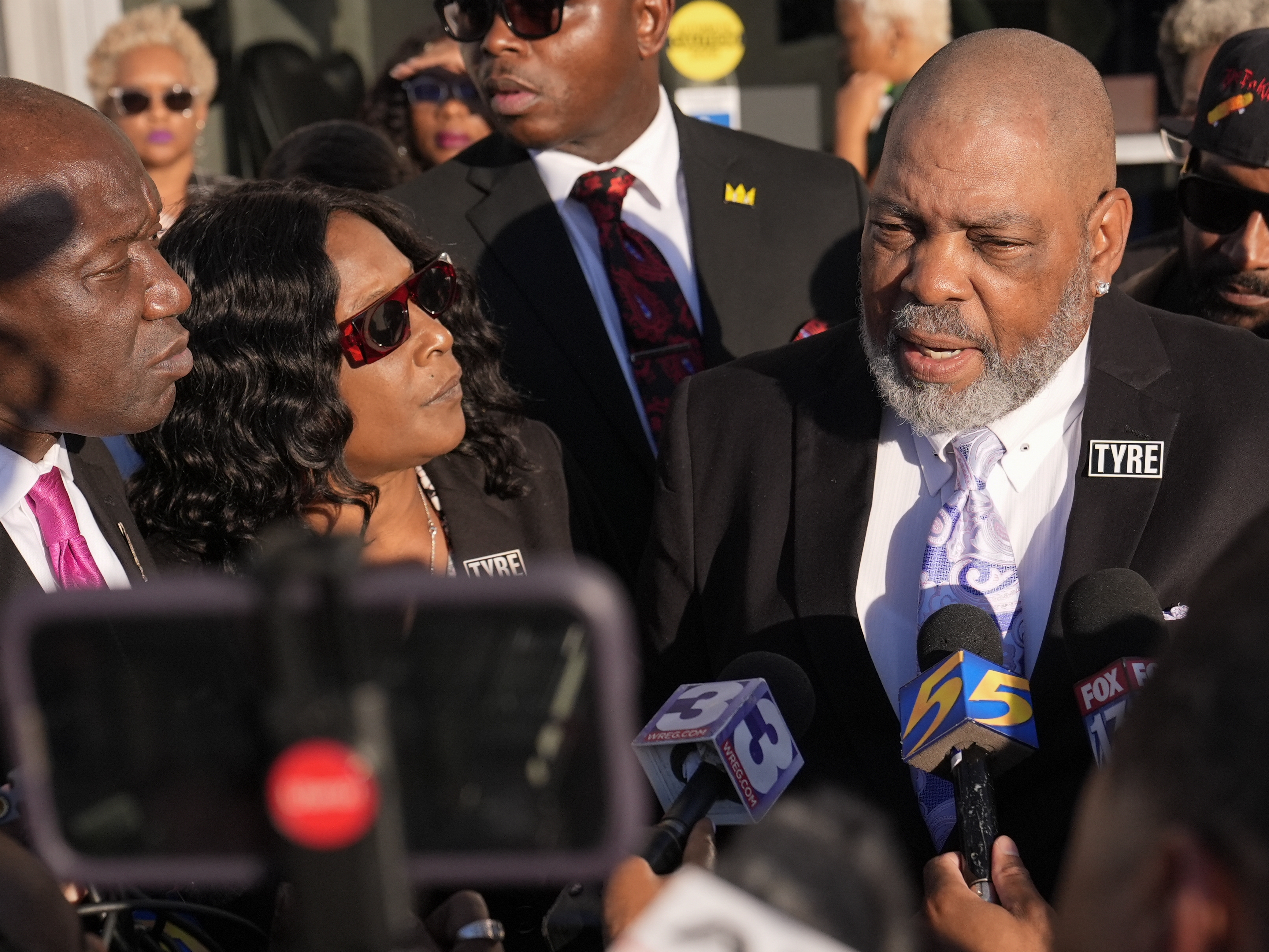 caption: Rodney Wells, right, stepfather of Tyre Nichols, speaks during a news conference with his wife RowVaughn Wells, center, and attorney Ben Crump, left, outside the federal courthouse Thursday after three former Memphis police officers were convicted of witness tampering charges in the 2023 fatal beating of their son in Memphis, Tenn.