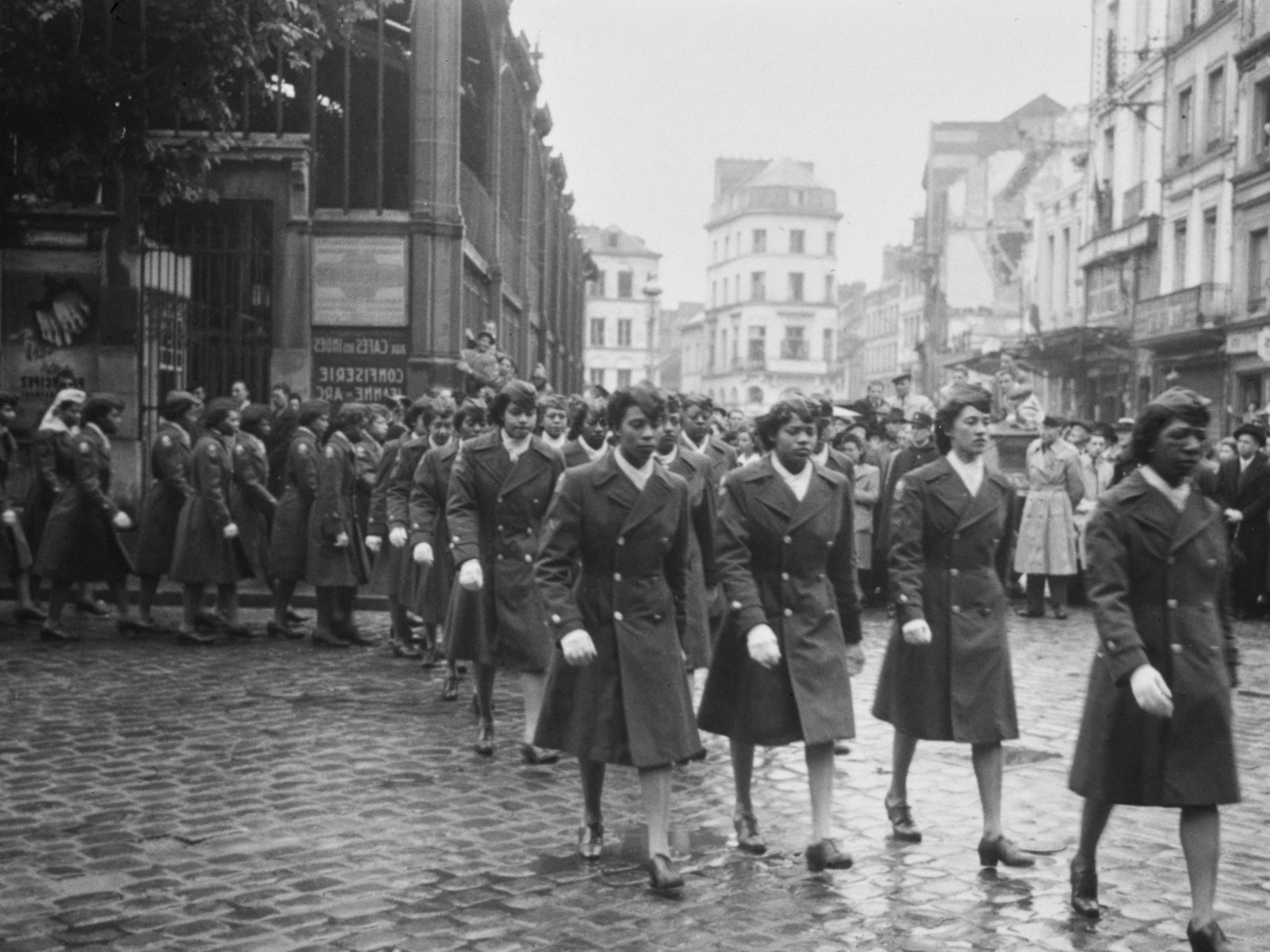 caption: Military personnel of the 6888th Central Postal Directory Battalion take part in a parade in honor of Joan d'Arc in Rouen, France, 1945. The predominantly-Black Six Triple Eight was the only all-female unit to serve overseas in WWII.