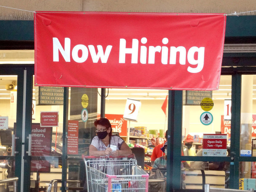 caption: A Now Hiring sign hangs near the entrance to a Winn-Dixie Supermarket in Hallandale, Florida.
