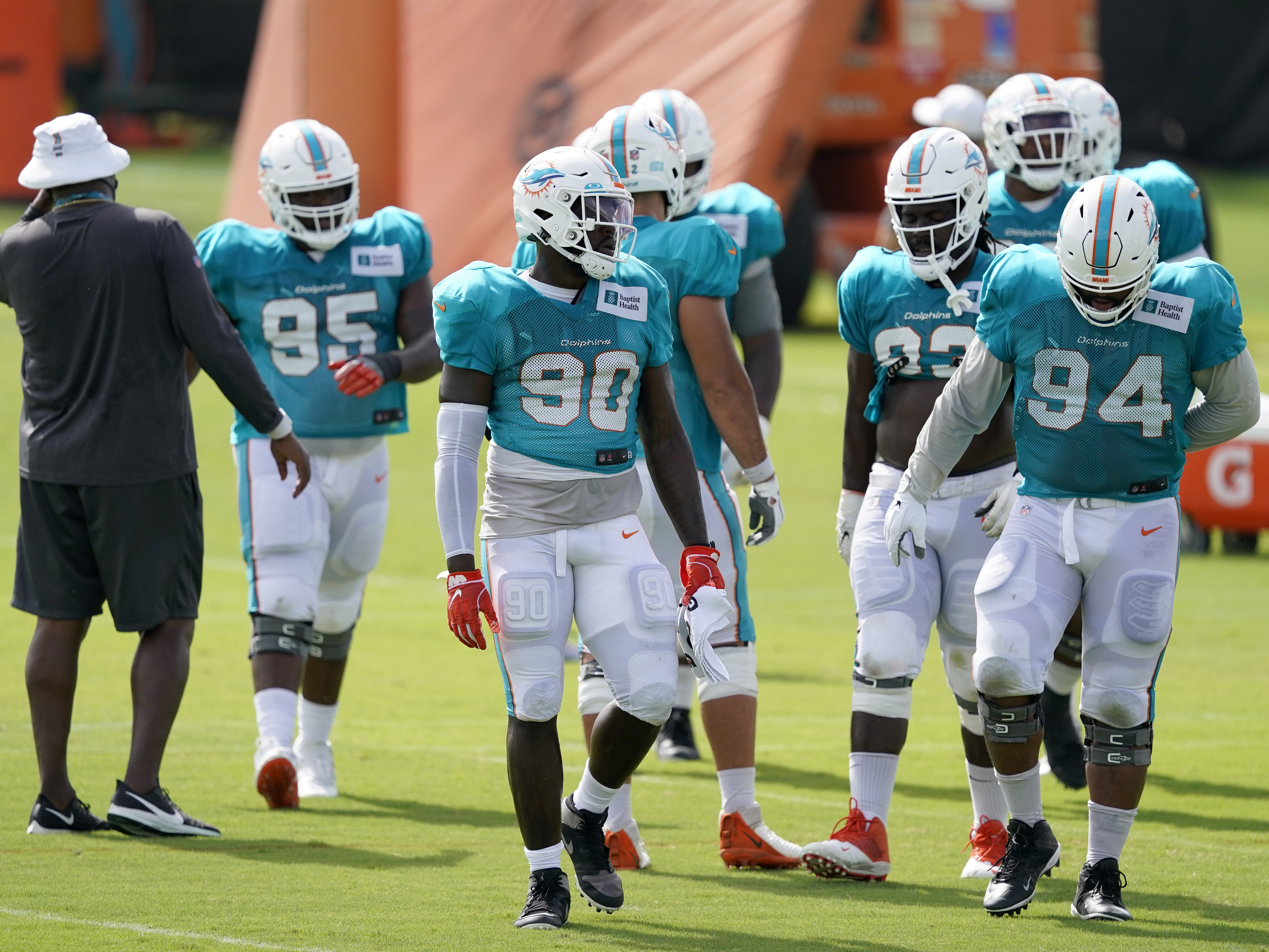 caption: Players for the Miami Dolphins take a break between practice drills during training camp last Friday. When the regular season begins, they'll be playing in front of a smaller-than-normal crowd due to coronavirus restrictions.