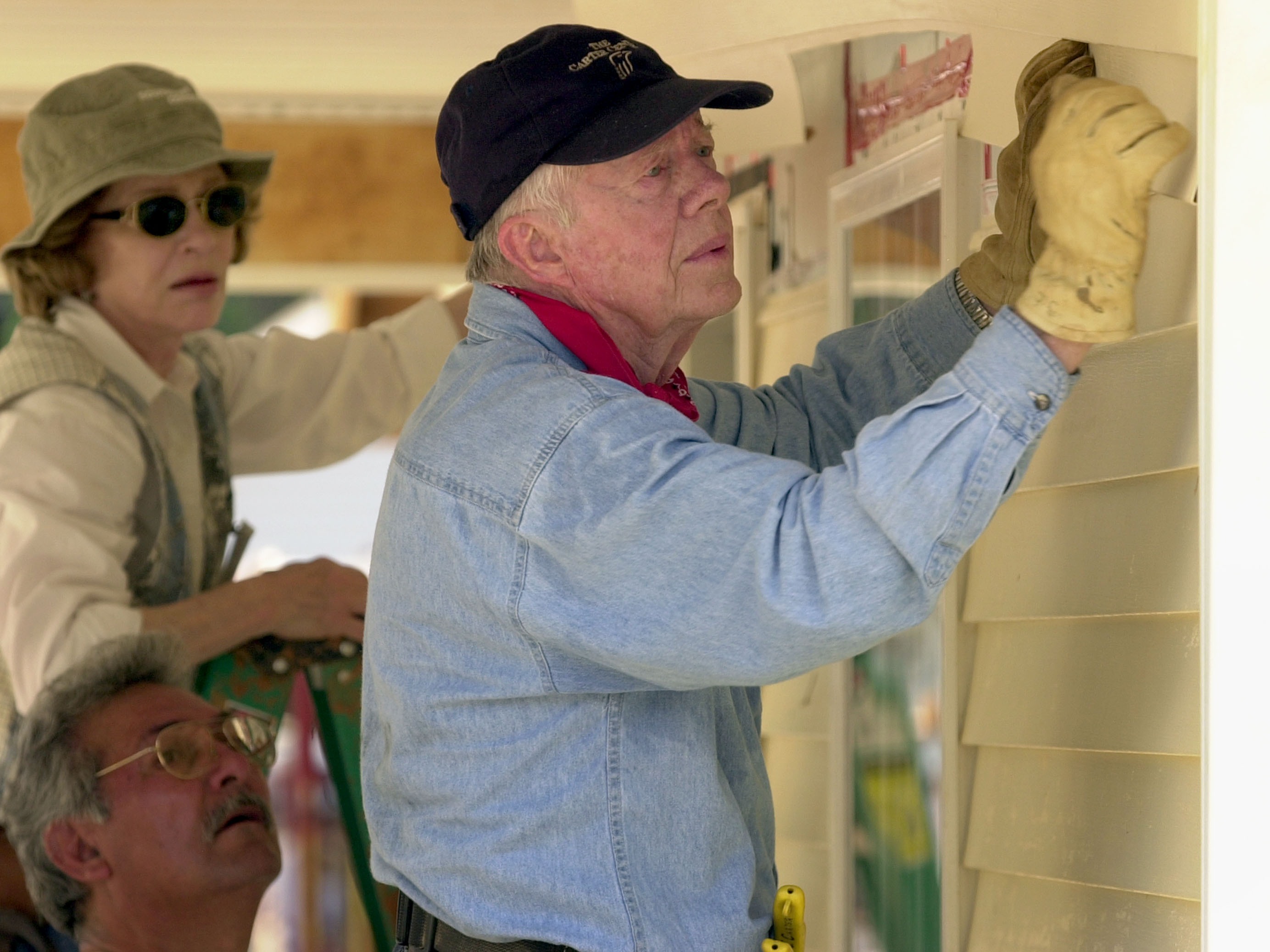 caption: Former President Jimmy Carter and his wife, Rosalynn Carter, attach siding to the front of a Habitat for Humanity home being built on June 10, 2003, in LaGrange, Georgia.