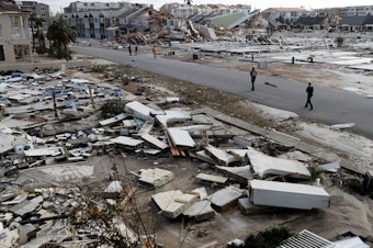 caption: Rescue personnel walk through debris as they search for people who need help in the aftermath of Hurricane Michael in Mexico Beach, Florida.
