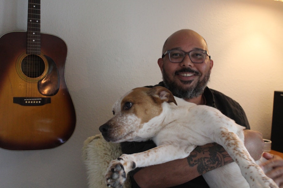 caption: Darren Fisher holds his dog, Arlo, in his Bothell home on July 29, 2023.