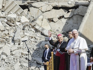 caption: The archbishop of Mosul, Najib Mikhael Moussa (left) waves as he stands next to Pope Francis at the start of a gathering to pray for the victims of war at the Hosh al-Bieaa Church Square, in Mosul, Iraq, once the de facto capital of ISIS on Sunday.