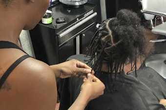 caption: Shana Bonner, left, styles the hair of Pho Gibson at Exquisite U hair salon in this July 3, 2019, file photo. The U.S. House passed a federal anti-bias bill to protect against discrimination of race-based hairstyles.