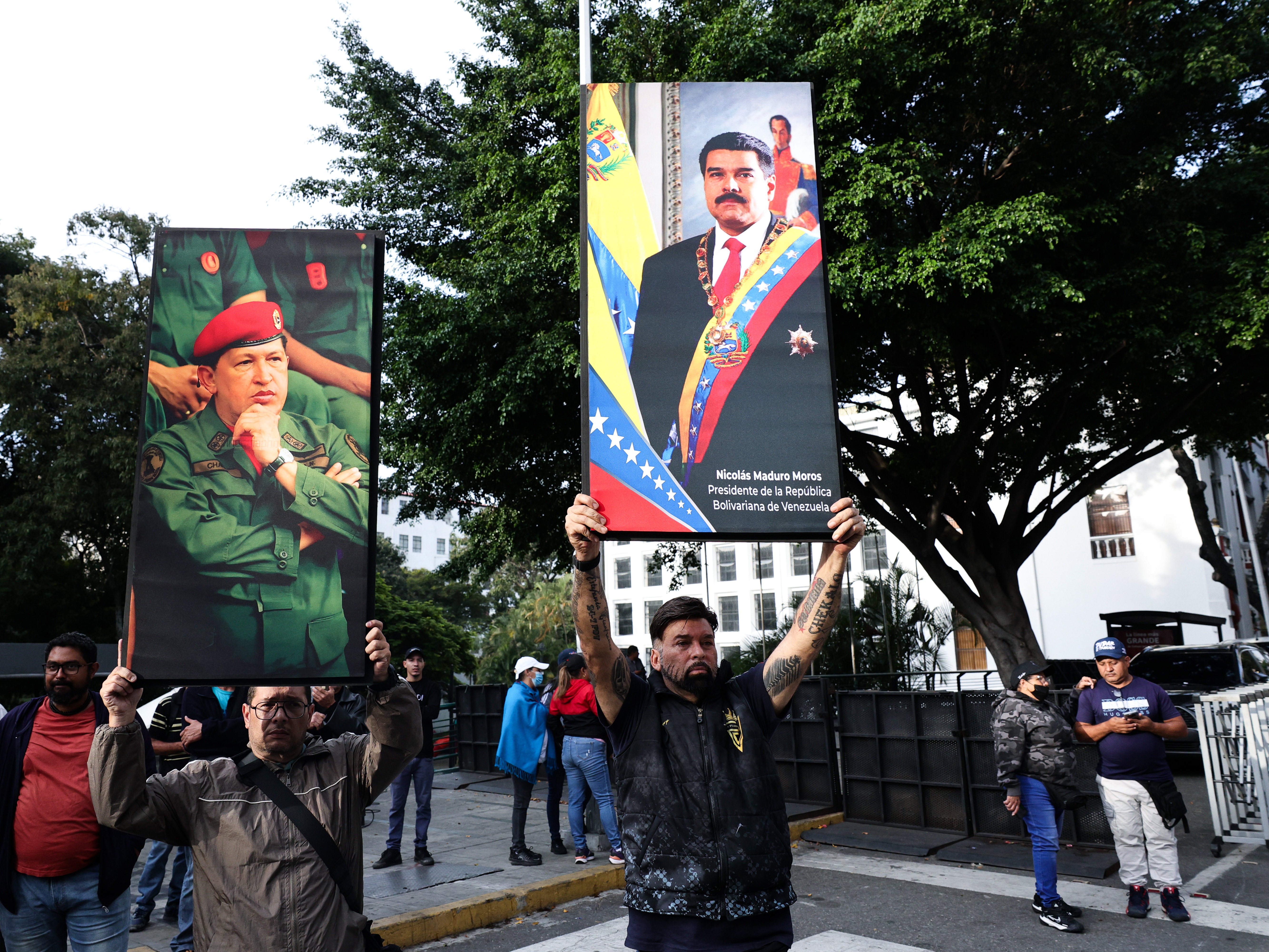 caption: Supporters of Venezuela's current and former president, Nicolas Maduro and the late Hugo Chavez, hold posters with their images in Caracas on Saturday.