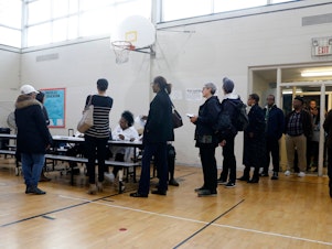 caption: People stand in line at a Detroit polling place during Michigan's March 10 presidential primary. As a result of the pandemic, the state's top election official is sending absentee ballot applications to every registered voter for August and November elections.