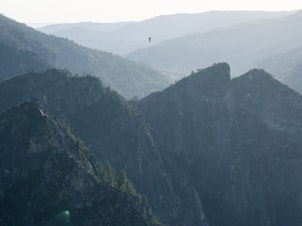 caption: Moises Monterrubio walks a highline 1,600 feet in the air in Yosemite in June. The line stretched 2,800 feet, setting a record for Yosemite and California.