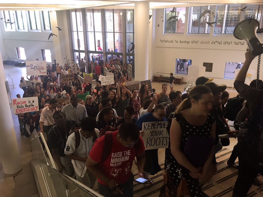 caption: Students and staff march through Suzallo Library during a walkout on Thursday, May 12, 2016, to protest racial inequity on campus.